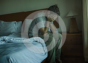 Dramatic lifestyle portrait of man sitting depressed on bed crying desperate feeling sad suffering anxiety crisis and depression