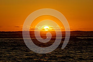 Dramatic lighting the sky and ocean during sunsets with light reflecting on ocean waves