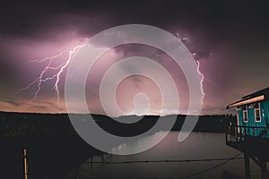 Dramatic lightning strikes illuminates building by summer lightning storm