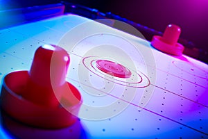 Dramatic lit air hockey table with puck and paddles