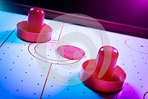 Dramatic lit air hockey table with puck and paddles