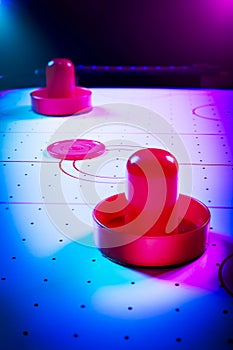 Dramatic lit air hockey table with puck and paddles