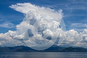 Dramatic looking clouds over sea. Billowing clouds hang over the ocean. Beautiful summer blue sky and white clouds over calm sea.