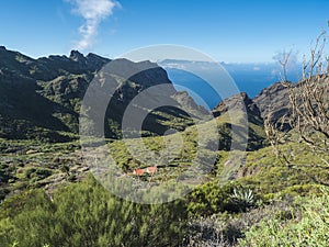 Dramatic lush green picturesque valley with old village Los Carrizales . Landscape with sharp rock formation, hills and photo