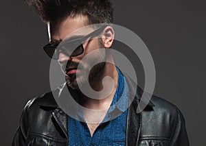 Dramatic man in sunglasses and leather jacket looks to side