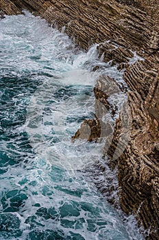 Dramatic marine background. Rocky coast of Adriatic Sea. White foamy waves beat against stone shore. Panorama of sea coast. Aerial