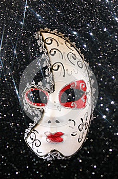 Dramatic and mysterious half moon carnival mask and black glitter background