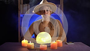 Dramatic of a mystic young fortune teller with a lighted crystal ball in her office, future vision