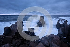 Dramatic nature background - big waves and dark rock in stormy sea, stormy weather. Dramatic scene.