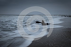 Dramatic nature background - big waves and dark rock in stormy sea, stormy weather. Dramatic scene.