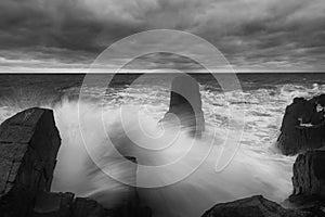 Dramatic nature background - big waves and dark rock in stormy sea, stormy weather. Dramatic scene.
