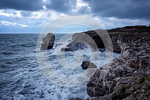 Dramatic nature background - big waves and dark rock in stormy sea, stormy weather. Dramatic scene.