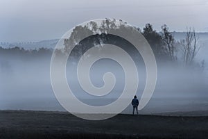 Man standing alone in the foggy nature