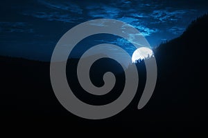 Dramatic Nighttime Moonrise Over Mountain Ridge and Pine Trees