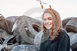 Dramatic photo of a cheerful girl at a tire repair dump. Waste disposal