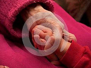 Dramatic photo of a grandma's hand holding her grandchild's hand