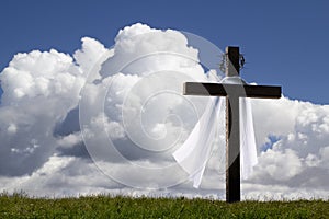 Dramatic photo illustration of Easter Morning with brilliant clouds, deep blue sky and large wooden cross, with shroud and crown o