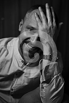 Dramatic portrait of an adult smiling man. Studio photography. Black and white image