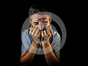 Dramatic portrait of attractive sad and depressed man with hands on his face crying desperate suffering depression and pain having