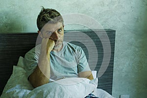 Dramatic portrait of attractive scared and depressed 40s man on bed in pajamas feeling worried suffering anxiety and depression