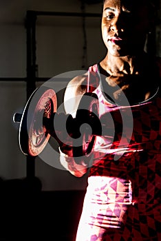 Dramatic portrait of fitness woman doing exercise for arm muscle