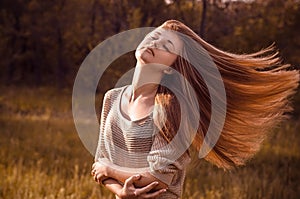 Dramatic portrait of a girl theme: portrait of a beautiful girl with flying hair in the wind against a background in the forest