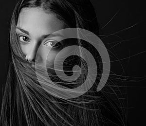 Dramatic portrait of a girl theme: portrait of a beautiful girl with flying hair in the wind against a background in the studio