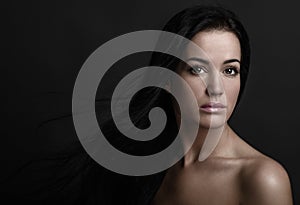 Dramatic portrait of a girl theme: portrait of a beautiful girl with flying hair in the wind against a background in the studio