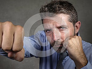 Dramatic portrait of middle aged upset and fierce businessman boxing throwing punch looking furious suffering work stress fighting