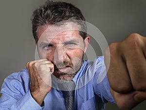 Dramatic portrait of middle aged upset and fierce man boxing throwing punch looking furious suffering work stress fighting for