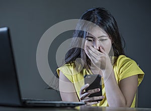 Dramatic portrait scared and stressed Asian Korean teen girl or young woman with laptop computer and mobile phone suffering cyber