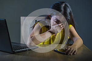 Dramatic portrait scared and stressed Asian Korean teen girl or young woman with laptop computer and mobile phone suffering cyber