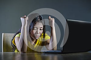 Dramatic portrait of scared and stressed Asian Korean teenager girl or young woman with laptop computer suffering cyber bullying s