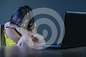 Dramatic portrait of scared and stressed Asian Korean teenager girl or young woman with laptop computer suffering cyber bullying s