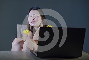 Dramatic portrait of scared and stressed Asian Korean teenager girl or young woman with laptop computer suffering cyber bullying s