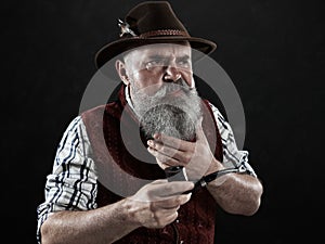 Dramatic portrait of senior smoking tobacco pipe