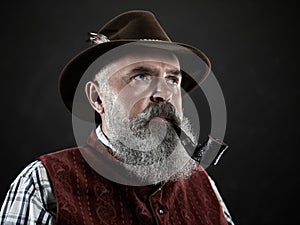 Dramatic portrait of senior smoking tobacco pipe