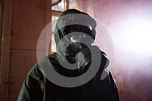 Dramatic portrait of a woman wearing a gas mask in a ruined building