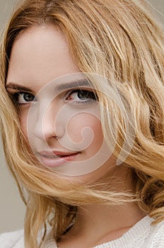 Dramatic portrait of a young beautiful blonde woman with long curly hair.