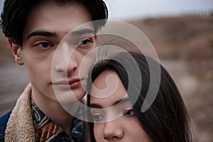 Dramatic portrait of a young brunette girl and a guy in cloudy weather.the girl leaned over the boy`s shoulder. selective focus,