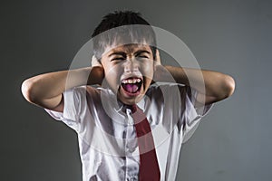 Dramatic portrait of young desperate and abused schoolboy in uniform crying alone victim of bullying and abuse at school