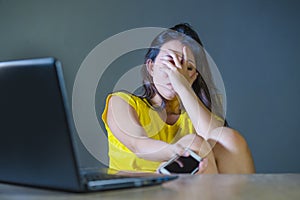 Dramatic portrait of young sad and scared woman covering face with hands stressed and worried looking at laptop computer isolated