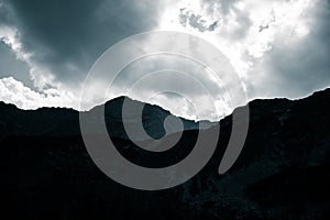 Dramatic rain clouds over the mountain top silhouette. Mountain landscape in summer.