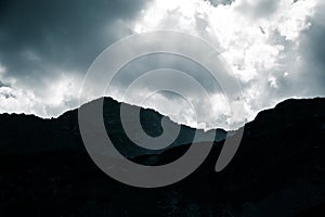 Dramatic rain clouds over the mountain top silhouette. Mountain landscape in summer.