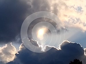 Dramatic rainy clouds with silver lining around the sun.