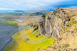 Dramatic rocky coastline landscape with green steep slopes, wild rocks and black beach, Iceland