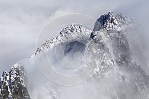Dramatic, rocky, snowy mountain peak ridge in between mist and clouds, High Tatras, Lomnicky Peak, Slovakia, European alps.
