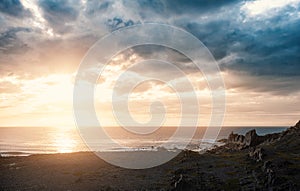 Dramatic scene with big rocks, sea, sunbeam and sundown