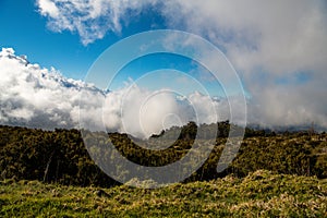 Dramatic scene of meadow and hills below a clearing storm and fog