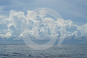 Dramatic scene of powerful raining white cloud, shades of blue sky background and deep blue sea with ocean water ripple